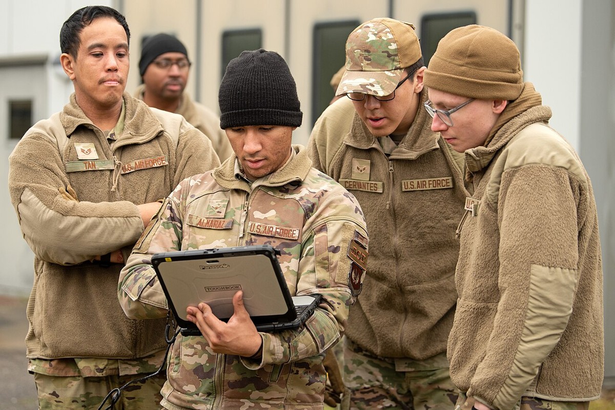 U.S. Air Force airmen gathered around a rugged Panasonic Toughbook laptop